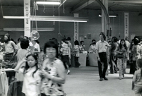 Market Day and Knitting Class, Item 12, front: Center: Fred Odanaka, workshop director (tall man wearing light-colored shirt and dark slacks)