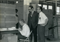 Workshop [Senior Work Center], Item 11, front: Mr. Nambu (far right) and Dr. Bruce Douglas (second from right) observe a worker busy at his task. Dr. Douglas, an Illinois state representative, was touring the work center