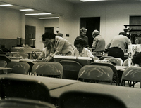 Weaving, Item 1, front: Weaving class at new Issei drop-in center. Mrs.Fricke (center foreground, standing)