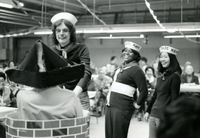 New Year's Party, Item 10, front: Skit performers (L to R) Cecilia Ishibashi (back to camera, wearing triangular hat) mental health supervisor Dennis Jennings, unidentified woman, and office secretary Kathy Harano