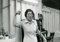 New Year's Party, Item 5, front: Workshop supervisor Joan Sumida at the microphone